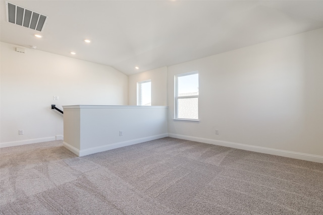 carpeted spare room featuring vaulted ceiling