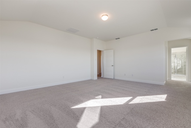 empty room featuring light colored carpet and lofted ceiling