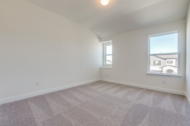 carpeted empty room with vaulted ceiling