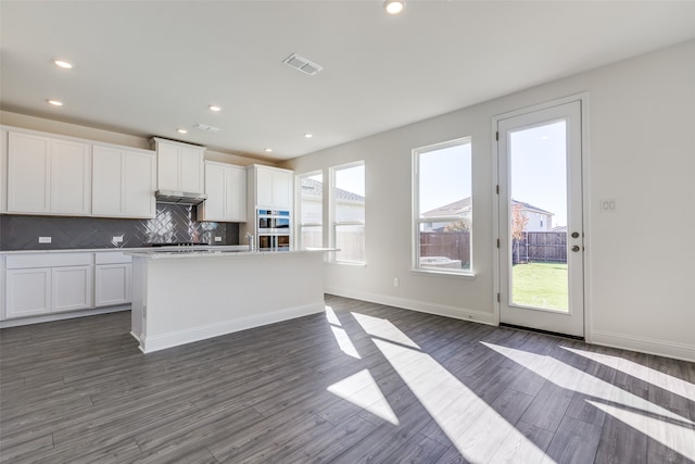 kitchen with a center island with sink, dark hardwood / wood-style floors, and white cabinetry