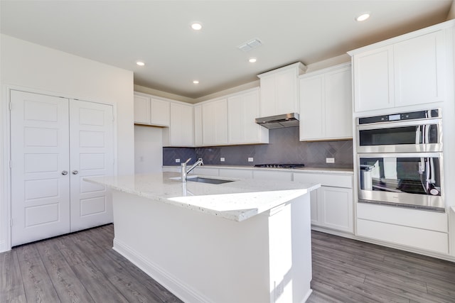 kitchen featuring hardwood / wood-style flooring, a center island with sink, sink, and appliances with stainless steel finishes