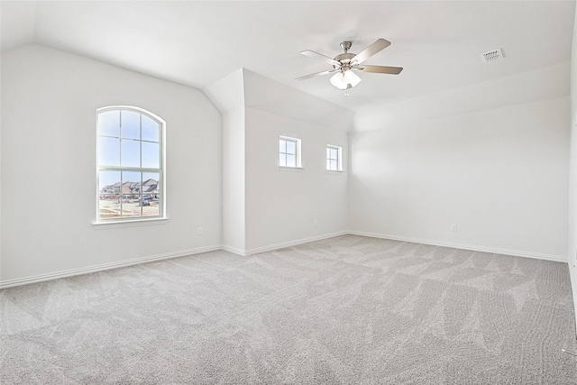 empty room with ceiling fan, light colored carpet, and vaulted ceiling