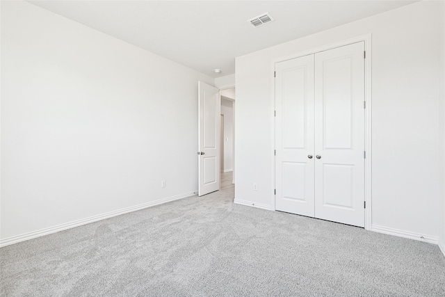 unfurnished bedroom featuring light colored carpet and a closet