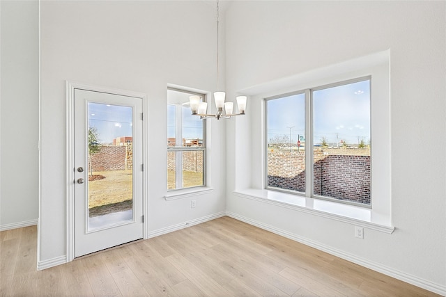 unfurnished dining area with light hardwood / wood-style floors and an inviting chandelier