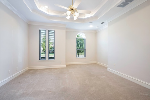 spare room with a tray ceiling, ceiling fan, crown molding, and light colored carpet