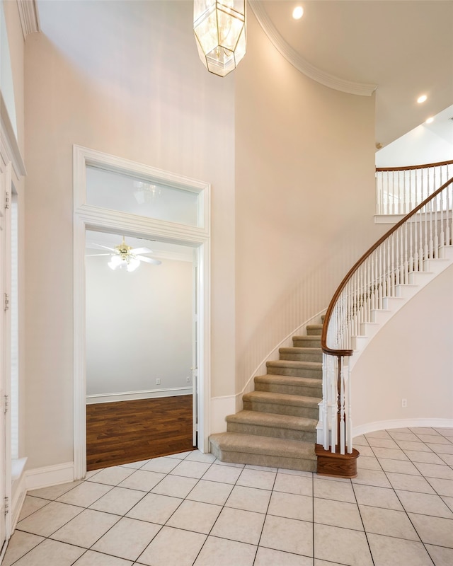 tiled foyer featuring a high ceiling, ceiling fan, and crown molding