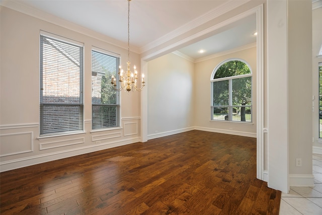 unfurnished dining area with hardwood / wood-style flooring, an inviting chandelier, and crown molding