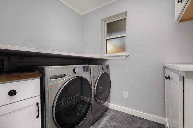 clothes washing area with cabinets, washer and dryer, and dark tile patterned floors