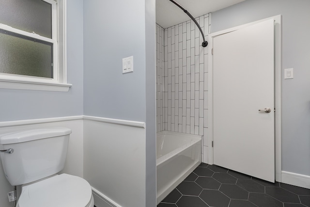 bathroom with tile patterned floors, toilet, and tiled shower / bath