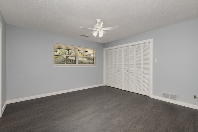 unfurnished bedroom with dark wood-type flooring, a closet, a textured ceiling, and ceiling fan