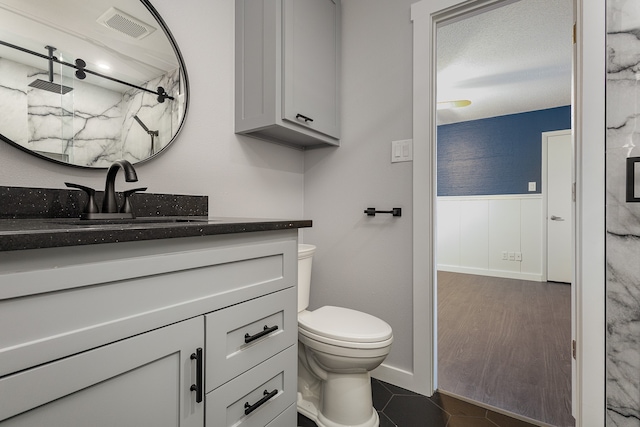 bathroom featuring walk in shower, toilet, wood-type flooring, vanity, and a textured ceiling