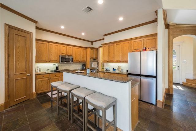 kitchen with tasteful backsplash, an island with sink, a kitchen bar, crown molding, and stainless steel appliances