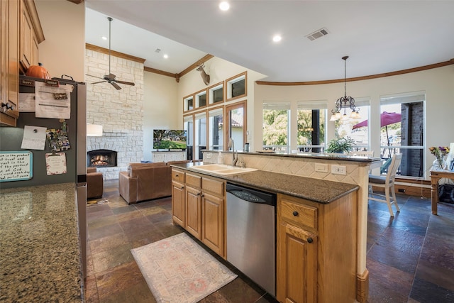 kitchen with hanging light fixtures, stainless steel appliances, dark stone counters, sink, and a fireplace