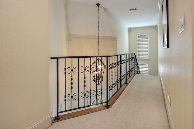 corridor with ornamental molding, a chandelier, and carpet flooring