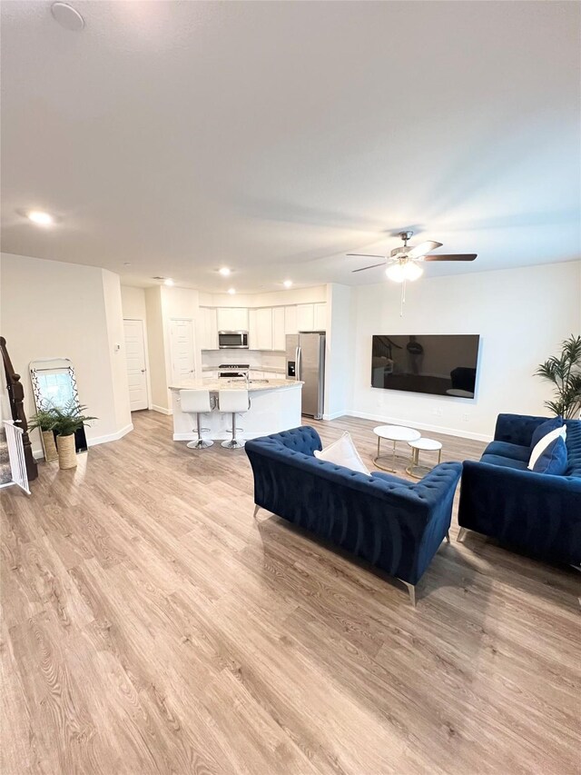 living room featuring sink, light hardwood / wood-style flooring, and ceiling fan