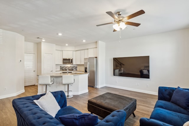 living room with ceiling fan, light wood-type flooring, and sink