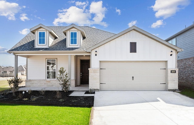 view of front of house featuring an attached garage, a shingled roof, driveway, board and batten siding, and a front yard