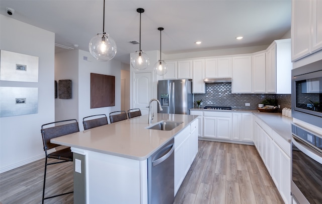 kitchen with appliances with stainless steel finishes, a kitchen island with sink, sink, and a breakfast bar