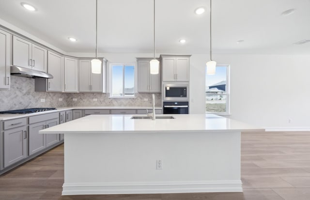 kitchen with gray cabinetry, a sink, gas cooktop, built in microwave, and oven