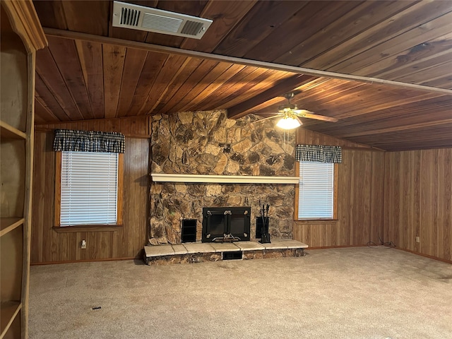 unfurnished living room with ceiling fan, wood walls, lofted ceiling with beams, wooden ceiling, and a fireplace