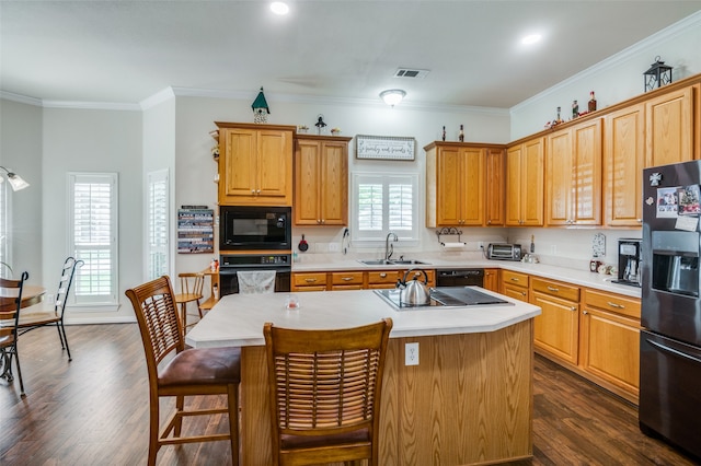 kitchen with black appliances, a kitchen island, sink, and dark wood-type flooring