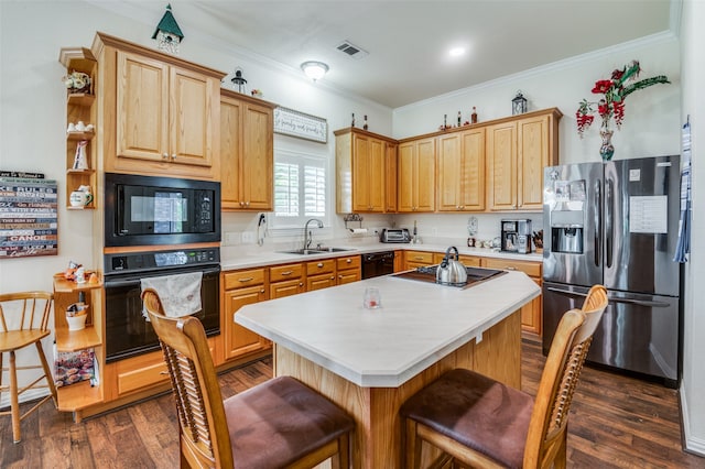 kitchen with dark wood-type flooring, sink, black appliances, a center island, and a breakfast bar area