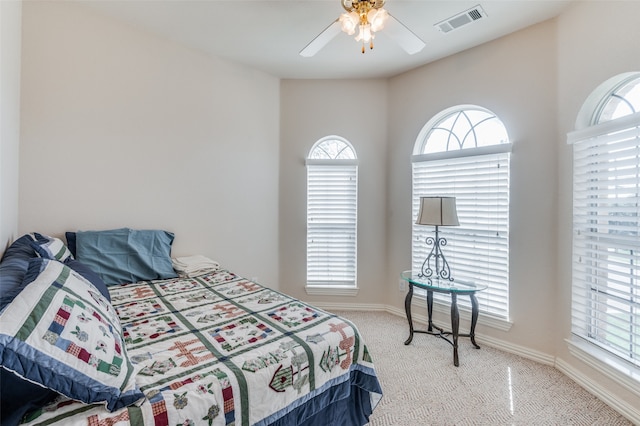 bedroom featuring light carpet, multiple windows, and ceiling fan