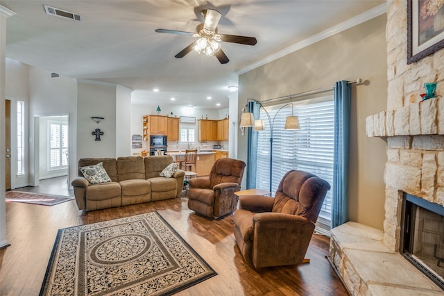 living room featuring a fireplace, light hardwood / wood-style floors, ceiling fan, and ornamental molding