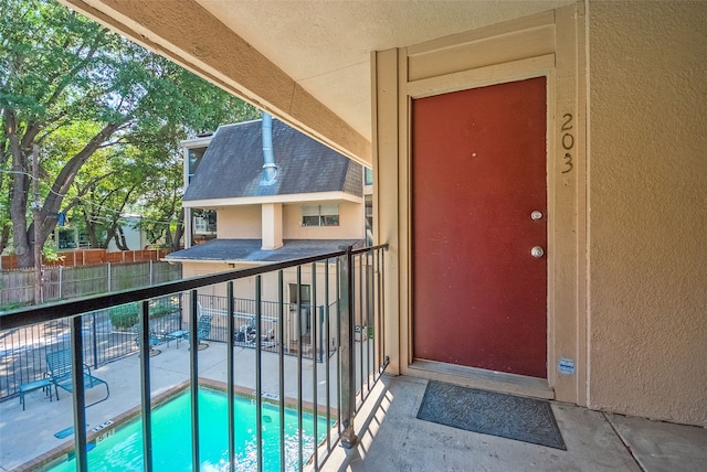 view of exterior entry with a community pool and a patio