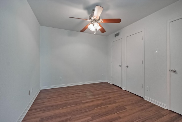 unfurnished bedroom with visible vents, baseboards, ceiling fan, and wood finished floors