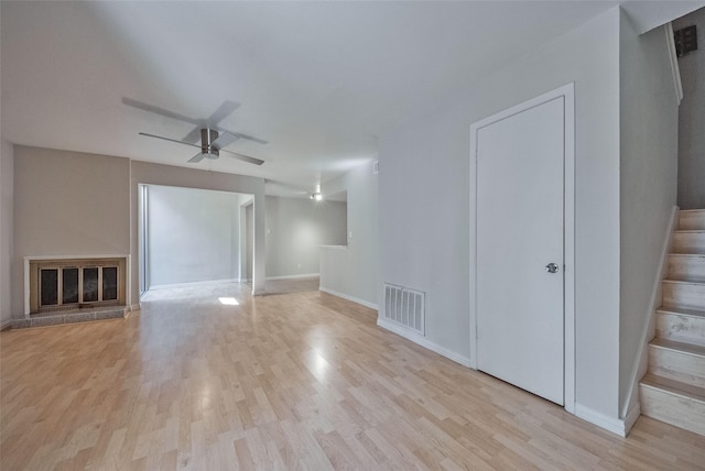 unfurnished living room with baseboards, stairway, visible vents, ceiling fan, and wood finished floors