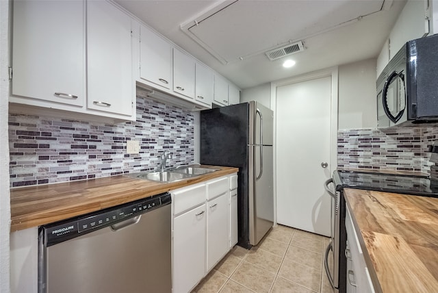 kitchen with appliances with stainless steel finishes, butcher block countertops, white cabinetry, and sink