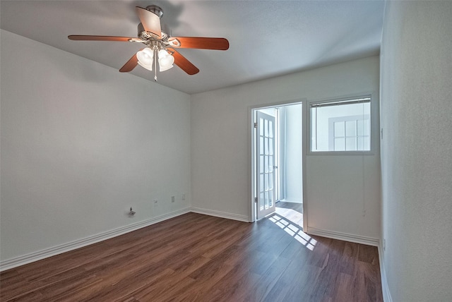 unfurnished room featuring ceiling fan, baseboards, and dark wood finished floors