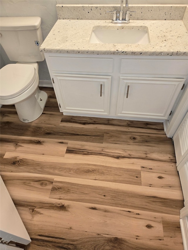 bathroom with toilet, vanity, and wood-type flooring