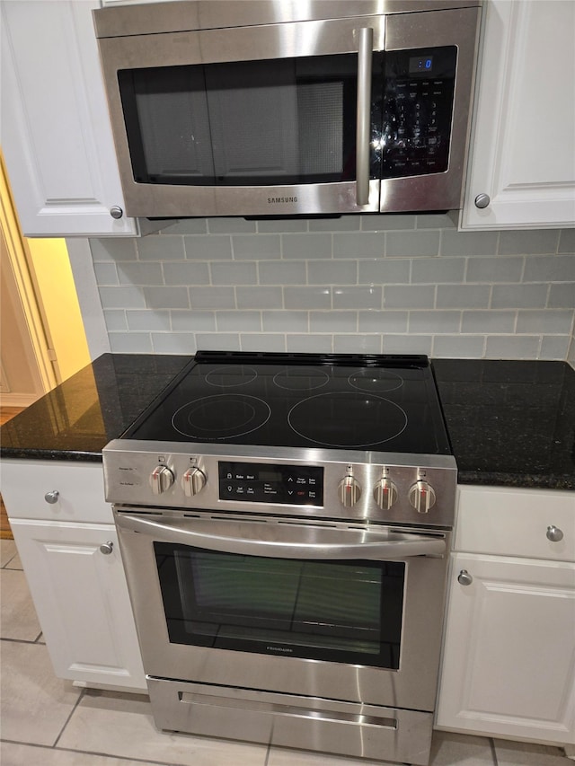 kitchen featuring appliances with stainless steel finishes, backsplash, dark stone counters, and white cabinetry