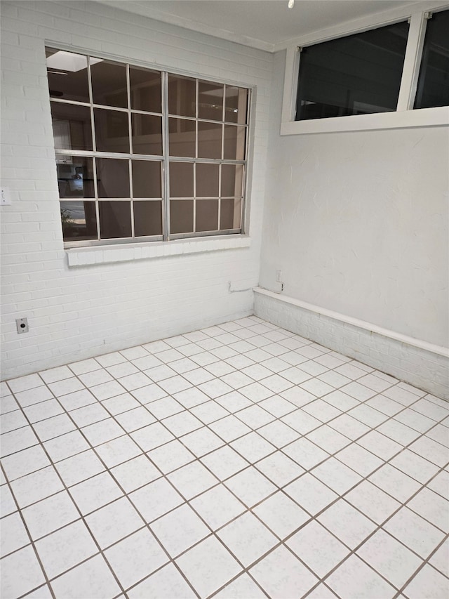 unfurnished room featuring brick wall and light tile patterned floors