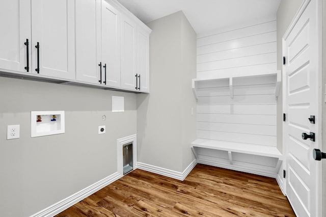 washroom with electric dryer hookup, hookup for a washing machine, light hardwood / wood-style flooring, and cabinets