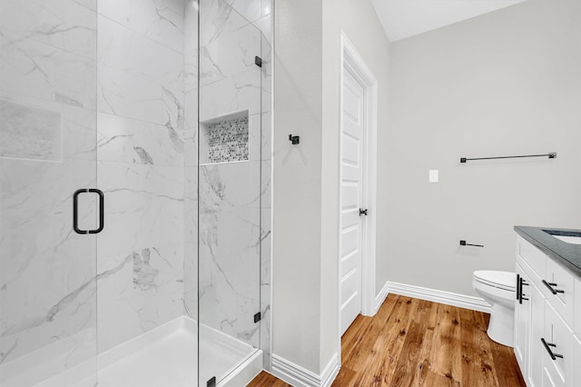 bathroom featuring wood-type flooring, vanity, toilet, and a shower with door