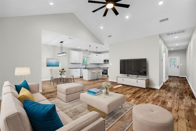 living room featuring light wood-type flooring, high vaulted ceiling, and ceiling fan