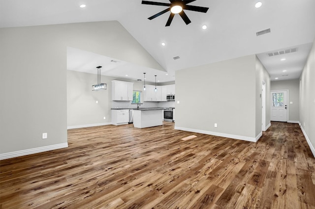 unfurnished living room with ceiling fan, wood-type flooring, and high vaulted ceiling