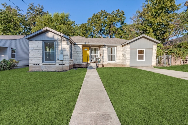 view of front of property featuring stone siding, fence, a front lawn, and roof with shingles