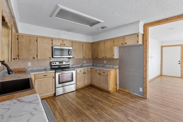 kitchen featuring backsplash, stainless steel appliances, sink, light hardwood / wood-style flooring, and a textured ceiling