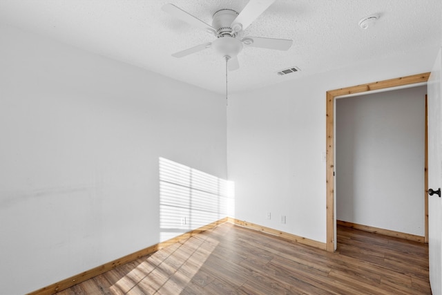 empty room with wood-type flooring, a textured ceiling, and ceiling fan