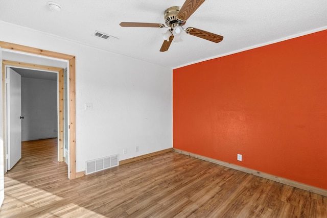 empty room featuring ceiling fan, light wood-type flooring, and ornamental molding