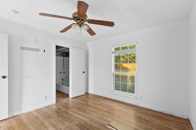 unfurnished room with ceiling fan, hardwood / wood-style floors, and a textured ceiling