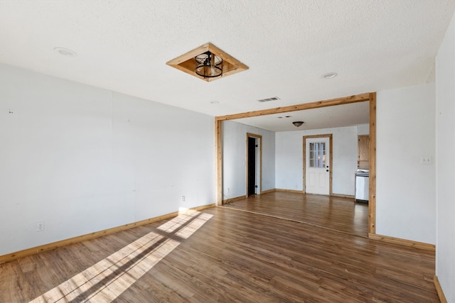 empty room featuring a textured ceiling and dark hardwood / wood-style flooring