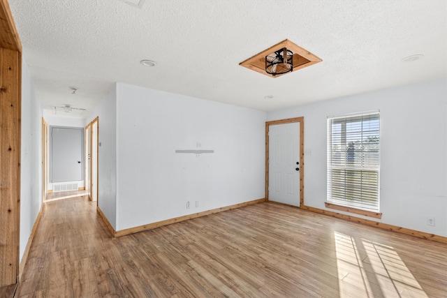 spare room featuring light hardwood / wood-style floors and a textured ceiling