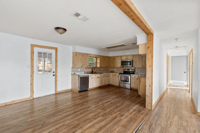 kitchen featuring hardwood / wood-style flooring, appliances with stainless steel finishes, a textured ceiling, and decorative backsplash