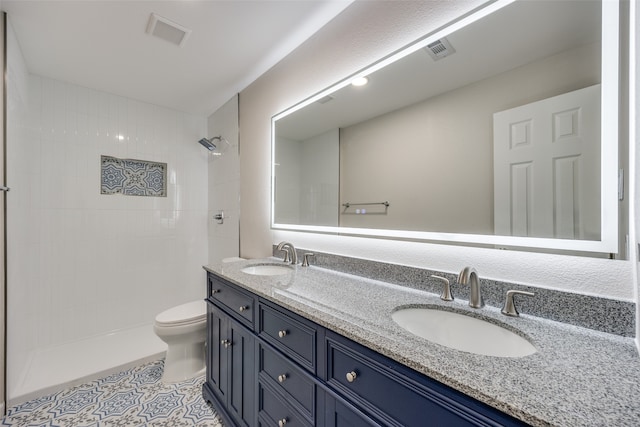 bathroom featuring toilet, vanity, tile patterned floors, and tiled shower