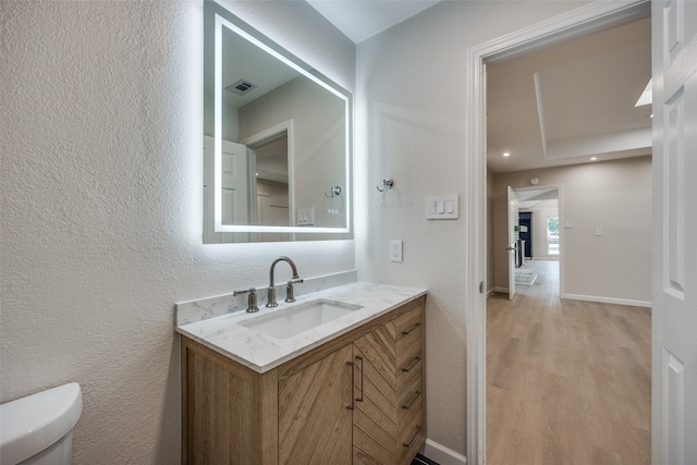 bathroom featuring toilet, hardwood / wood-style flooring, and vanity